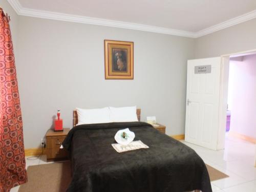a bedroom with a bed with a black blanket at Royal Castle Guest House in Windhoek