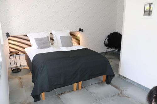 a bed with a black blanket and white pillows at Hotel Petite B&B in Haderslev