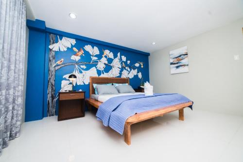 a bedroom with a bed with a blue wall at JSB Suites in Dipolog