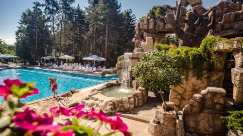 a pool at a resort with pink flowers in the foreground at Spa Hotel Dvoretsa in Velingrad