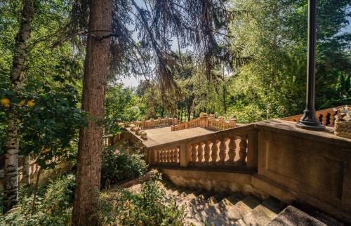 a stone bridge in a park with trees at Spa Hotel Dvoretsa in Velingrad