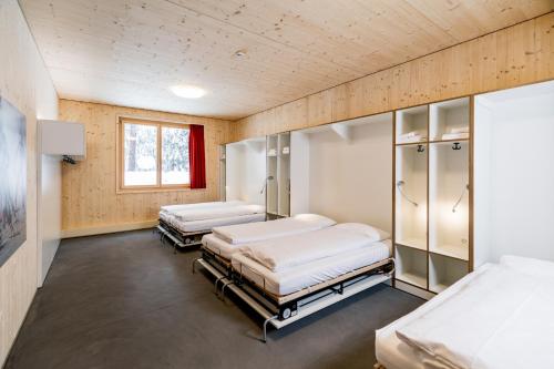 two beds in a hospital room with a window at Nordic Hostel in Lenzerheide