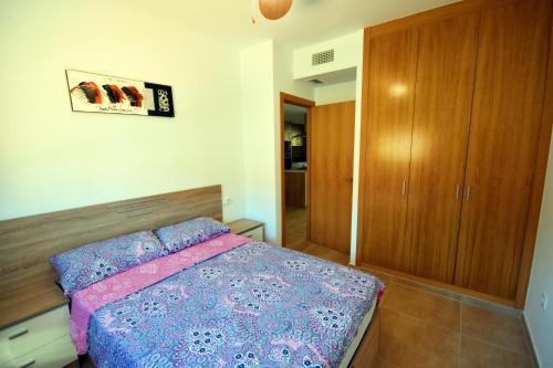 Un dormitorio con una cama y un armario de madera. en HE Villamartin Gardens, en Orihuela