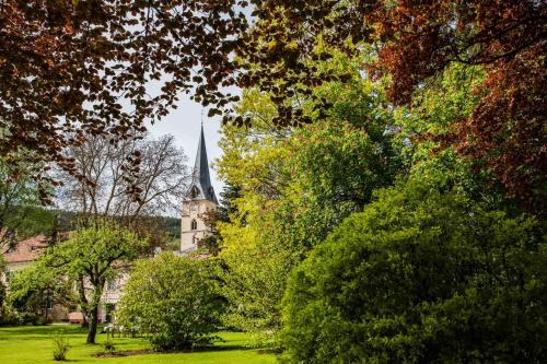 a church with a steeple is seen through the trees at Brunnwirt Kassl in Guttaring