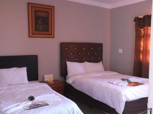 a bedroom with two beds with white sheets at Royal Castle Guest House in Windhoek