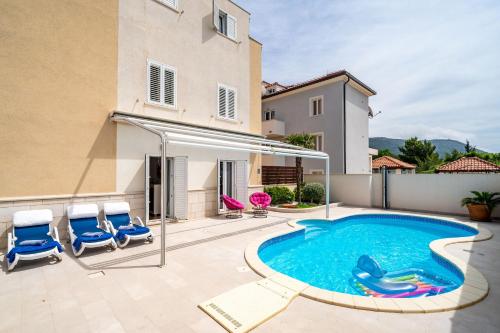 a swimming pool with two blue chairs and a house at Lorena Suite with private pool in Dubrovnik