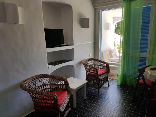 a living room with two chairs and a table and a television at Balaia Gardens, jardins da Balaia in Albufeira