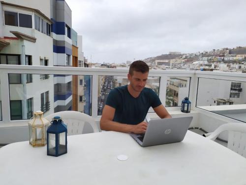 een man aan een tafel met een laptop bij CoolivingC in Las Palmas de Gran Canaria