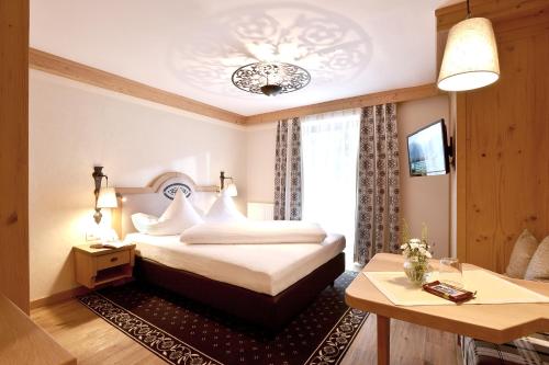 a hotel room with a bed and a table at Alpenhotel Kramerwirt in Mayrhofen