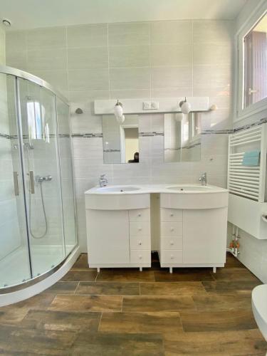a white bathroom with two sinks and a shower at La Petite Coccinelle in Noisy-le-Grand