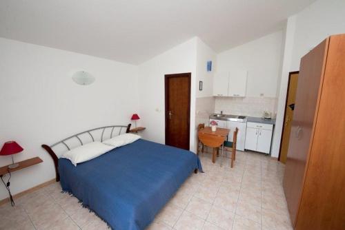 a bedroom with a blue bed and a kitchen at Studio Apartment in Duce with Sea View, Balcony, Air Conditioning, Wi-Fi (132-4) in Duće