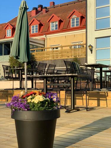 a patio with a table and an umbrella and flowers at Halltorps Gästgiveri in Borgholm
