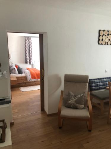 a living room with a chair and a bedroom at Haus am Wald in Neustift im Stubaital