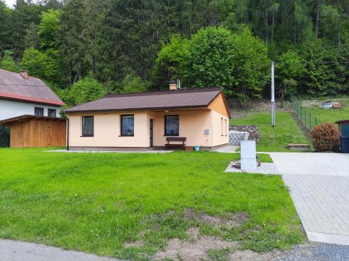 a small house in a yard with a green lawn at Líšný 105 celý nový dům se zahradou u Jizery a cyklo-stezky New house by Jizera river and bicycle path in Železný Brod