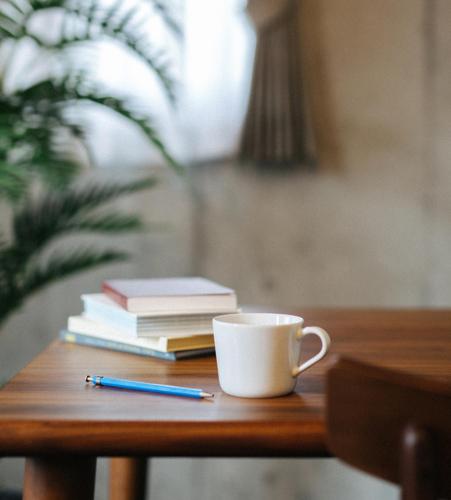 a cup of coffee and books on a table with a pen at treeside in Yugawara