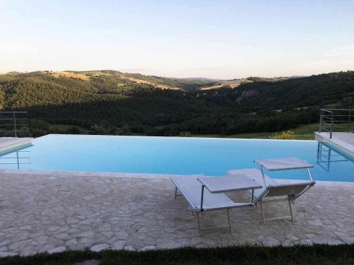a pool with two chairs sitting next to it at San Venanzo - Casale de Conti in San Venanzo