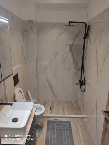 a bathroom with a shower and a white sink at Pink rose luxury and comfort apartment at the centre of Preveza in Preveza