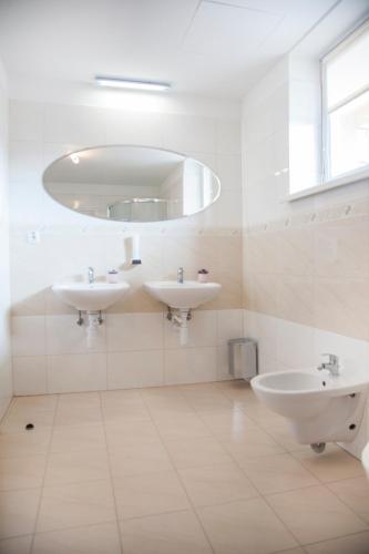 a white bathroom with two sinks and a mirror at Hotel Eminent in Stupava