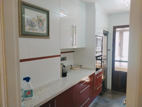 une cuisine avec des placards blancs et un comptoir dans l'établissement Apartamento Argandona-Gijon, à Gijón
