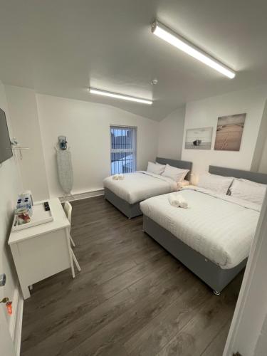 een slaapkamer met 2 bedden, een bureau en een raam bij County road rooms in Liverpool