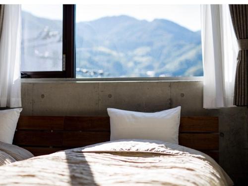 a bedroom with a bed with a large window at treeside in Yugawara