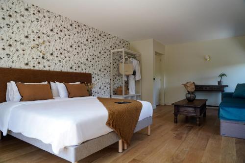 a bedroom with a large white bed and a blue couch at Hôtel Le Mouton Bleu in Talloires