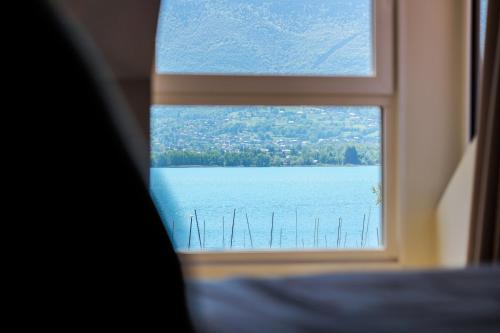 a window with a view of a body of water at Hôtel Le Mouton Bleu in Talloires