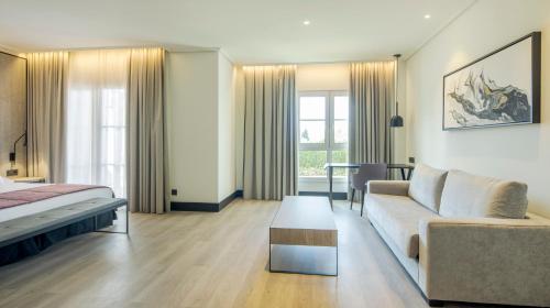 a large living room with a couch and a bed at Ilunion Alcora Sevilla in San Juan de Aznalfarache
