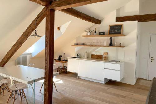 Design Apartment in the heart of Bolzano في بولسانو: مطبخ مع دواليب بيضاء وطاولة طعام