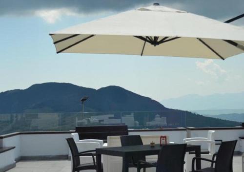a patio with a table and chairs and an umbrella at Hotel Monte Campo in Capracotta