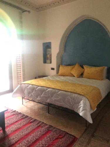 a bedroom with a large bed with a green headboard at Les Jardins de Ryad Bahia in Meknès