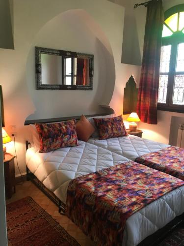 a bedroom with a bed and a mirror at Les Jardins de Ryad Bahia in Meknès