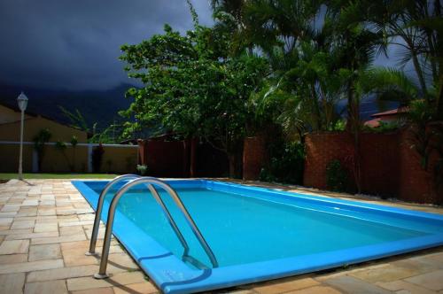 a blue swimming pool with a slide in a yard at Chalé Massaguaçu in Caraguatatuba