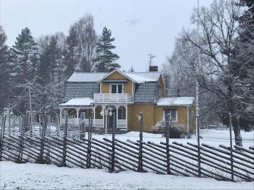 a yellow house with a fence in the snow at Härlig Heden Vakantiehuis in Råda