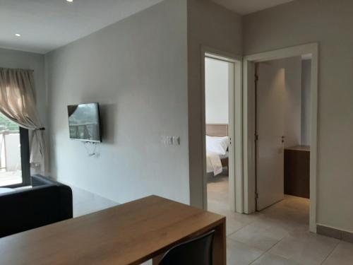 a living room with a table and a television on the wall at Forest View Apartments in Kololi