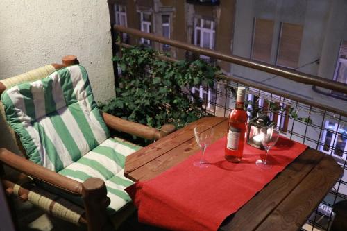 een houten tafel met een fles wijn en twee glazen bij Fornax Home with balcony in Boedapest