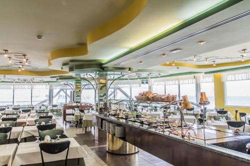 a restaurant with white tables and chairs and windows at KAKTUS Hotel Benikaktus in Benidorm