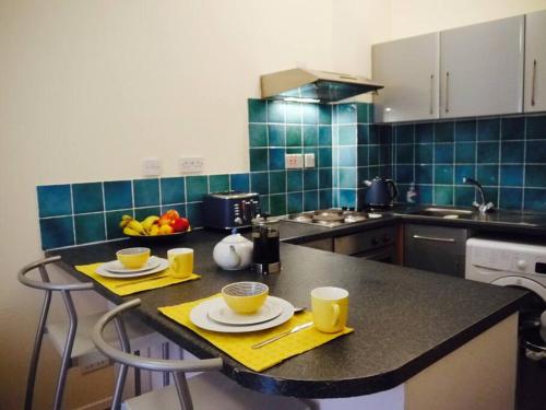 a kitchen with a table with two cups and a bowl of fruit at Fabulous location, One Bedroom West End Flat, just off Byres rd, close to SEC & Hydro in Glasgow