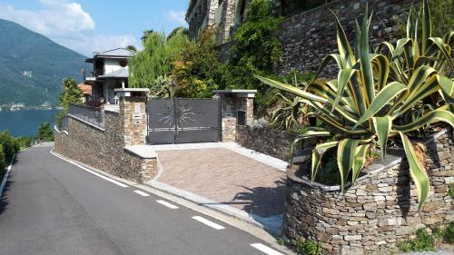 a gate on a stone wall next to a road at Sole & Lago-Lake in Maccagno con Pino e Veddasca