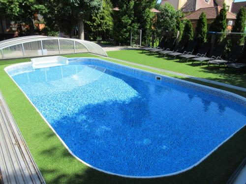 een groot blauw zwembad met ligstoelen in de tuin bij The Boys Apartman in Siófok