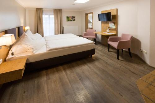 WeicheringにあるLandgasthof Vogelsang OHGのベッドとデスクが備わるホテルルームです。