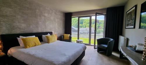 een slaapkamer met een bed en een groot raam bij Hôtel WELLNESS EAU DE ROCHE Durbuy in Durbuy