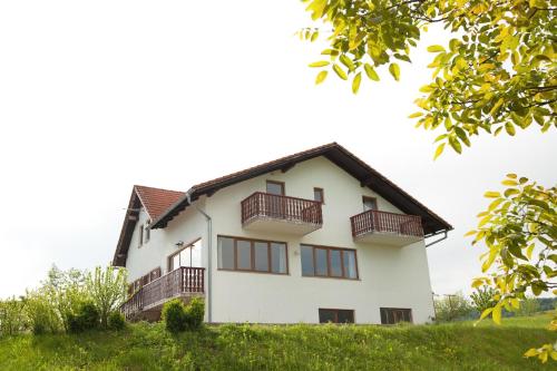 une maison blanche avec balcon sur une colline dans l'établissement Guesthouse Zafran, à Smoljanac