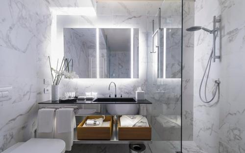 een badkamer met een wastafel en een douche met een spiegel bij Villaverde Hotel Spa&Golf Udine in Fagagna