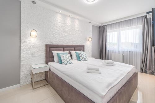 a bedroom with a large bed with blue and white pillows at Stylish Vacation Apartment with Parking in Międzyzdroje by Renters in Międzyzdroje