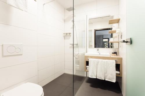 a bathroom with a shower and a toilet and a sink at Hotel Smart Liv'in in Böheimkirchen