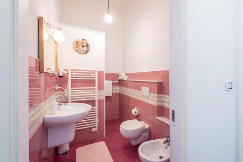 a pink bathroom with a sink and a toilet at Maria Vittoria Charming Rooms and Apartments in Brindisi