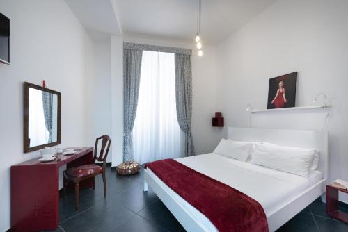 a bedroom with a white bed and a desk and a chair at Maria Vittoria Charming Rooms and Apartments in Brindisi