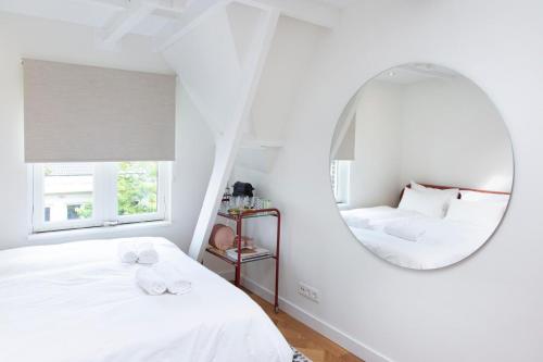 a white bedroom with a mirror and two beds at Trendy 2 bedroom accommodation on perfect location in Amsterdam