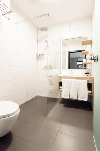 a white bathroom with a toilet and a sink at Hotel Smart Liv'in in Böheimkirchen
